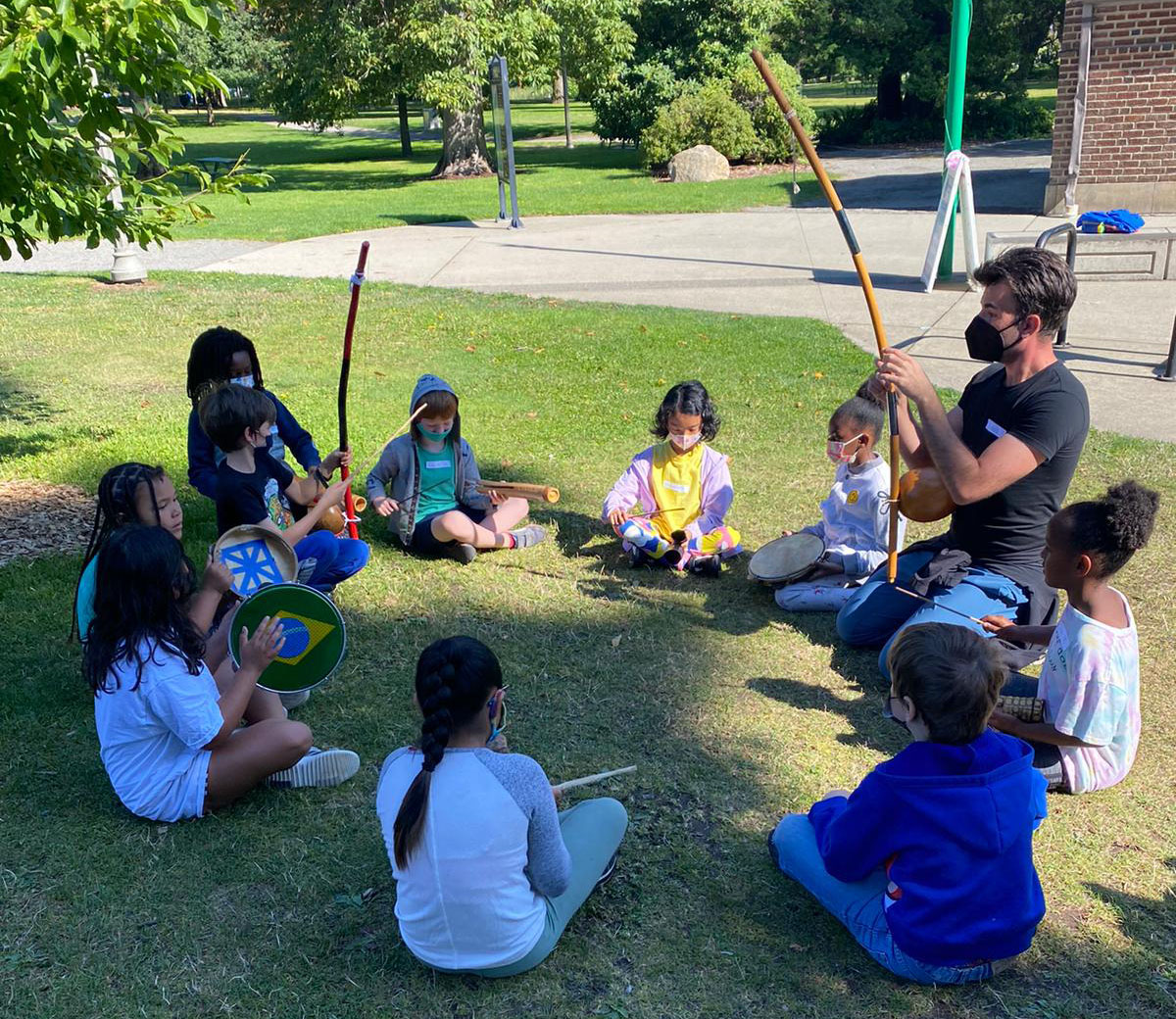 Kids training capoeira music instruments at the park.